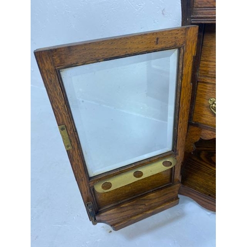 413 - Antique Smokers cabinet, in light oak, part glazed doors opening to show drawers and pipe rack  appr... 