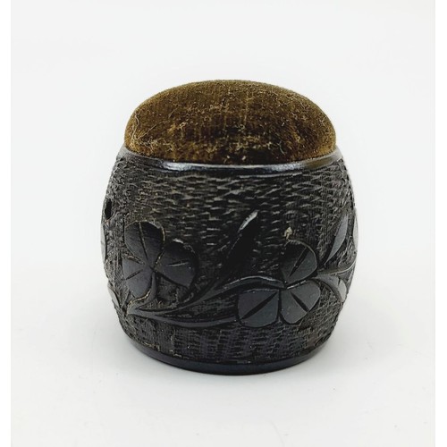 300 - An antique ebony pin cushion carved with clover leaves and the crest of Alston, height 1.5