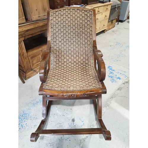 128 - A large hardwood and wicker carved rocking chair. No shipping. Arrange your own packer and shipper, ... 