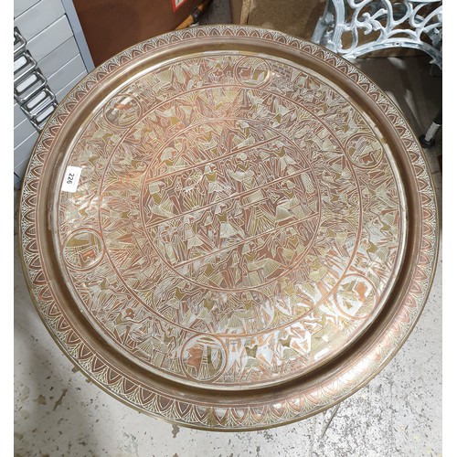 226 - A table, the top a brass charger with Egyptian motifs on a hardwood stand, diameter 23.25