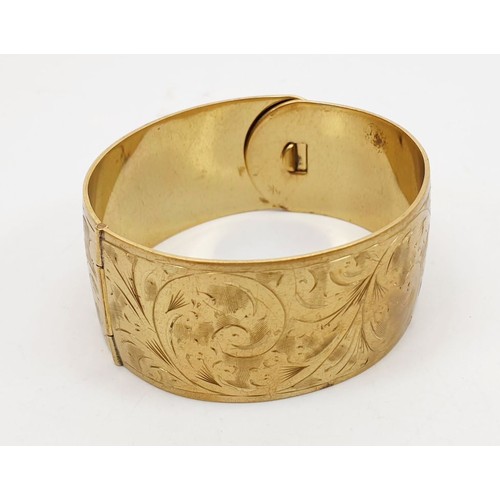 263 - A gilt metal bangle engraved with scroll work. UK shipping £14.