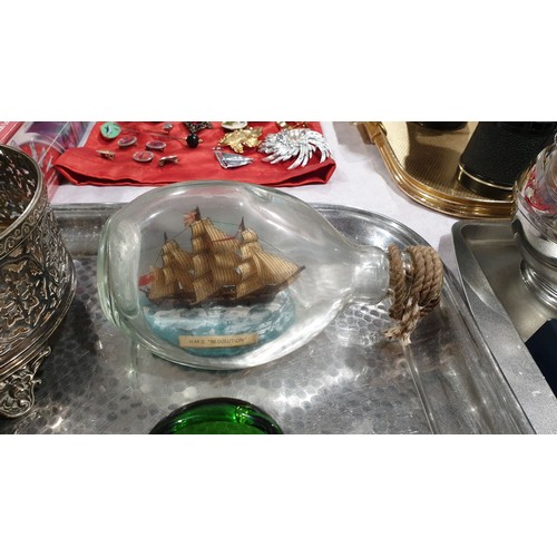 44 - A silver plated condiment holder with two bottles, a ship in a bottle, a money box and an eye bath. ... 