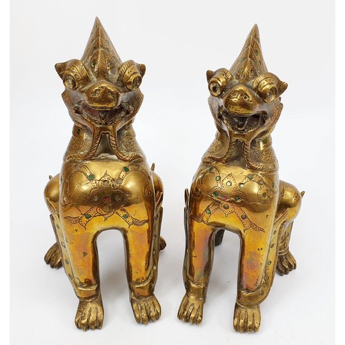 200 - A pair of antique brass Burmese mythical Chinthe inlaid with green glass, height 7.5