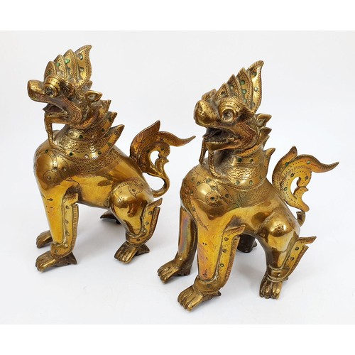 200 - A pair of antique brass Burmese mythical Chinthe inlaid with green glass, height 7.5