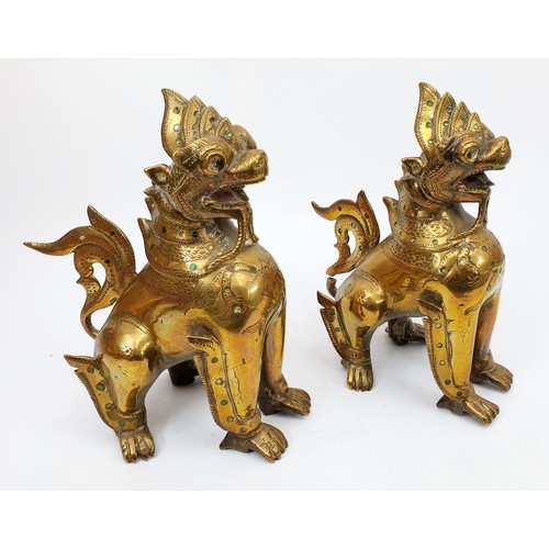 200 - A pair of antique brass Burmese mythical Chinthe inlaid with green glass, height 7.5