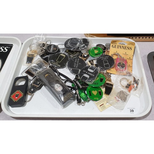 39 - A selection of vintage and later Guinness keyrings, bottle openers and badges. UK shipping £14.