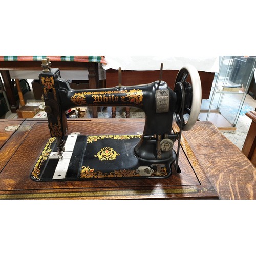 145 - An antique White sewing machine on a cast iron and oak treadle. No shipping. Arrange collection or y... 