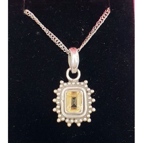 35 - A white metal pendant set with a yellow stone on a silver chain. UK shipping £14.