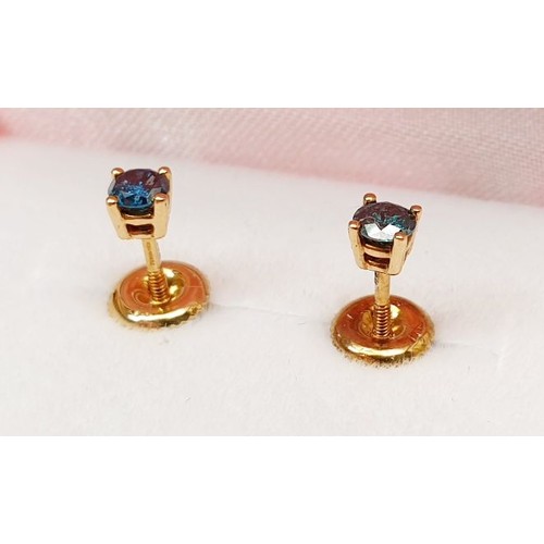 37 - A pair of hallmarked 14ct earrings set with teal-blue diamond and having screw backs. UK shipping £1... 