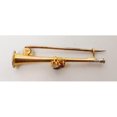 18 - A yellow metal brooch in the form of a trumpet set with diamond, sapphire and ruby, length 1.75