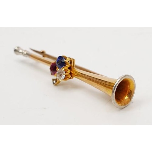 18 - A yellow metal brooch in the form of a trumpet set with diamond, sapphire and ruby, length 1.75