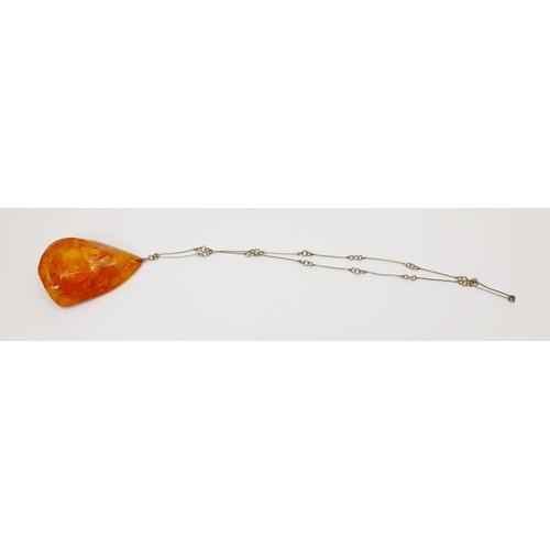 21 - A large amber pendant with butterscotch inclusions, pendant length 8.5cm, on a silver plated chain, ... 