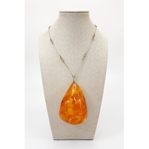 21 - A large amber pendant with butterscotch inclusions, pendant length 8.5cm, on a silver plated chain, ... 