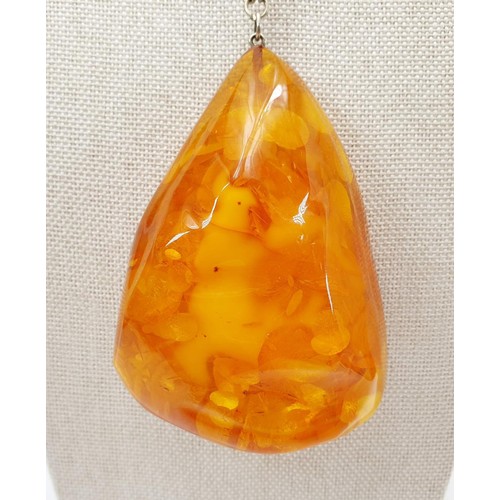 21 - A large amber pendant with butterscotch inclusions, pendant length 8.5cm, on a silver plated chain, ... 