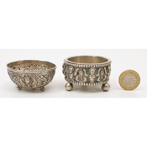 57 - Two far eastern white metal condiment type bowls each embossed with deities and foliage, the largest... 