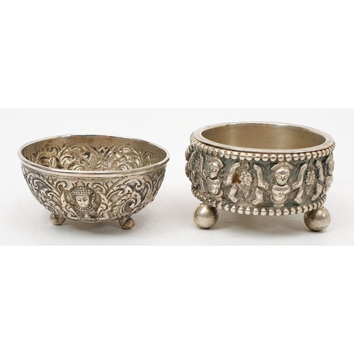 57 - Two far eastern white metal condiment type bowls each embossed with deities and foliage, the largest... 