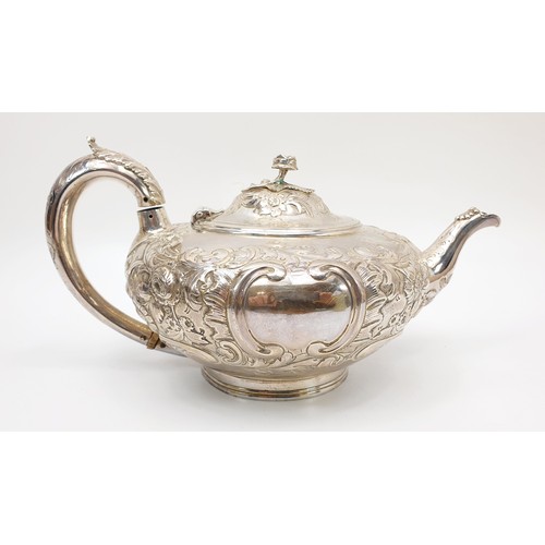 31 - A Victorian hallmarked silver teapot of squat form, heavily embossed with Rococo decoration and a fl... 