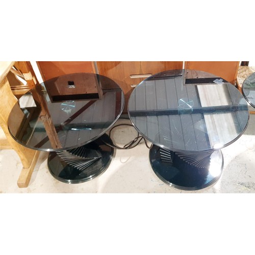 134 - A smokey glass spiral oval coffee table, width 120cm together with two matching circular tables, dia... 