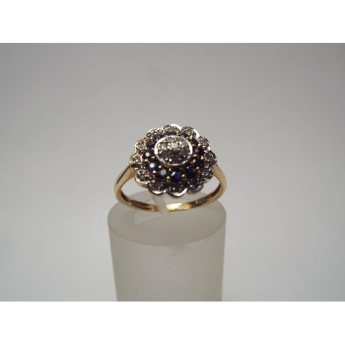 61 - 9ct Gold Diamond & Sapphire ring set in flower pattern.  2.8g Fomger size 'R'  IIV of £350