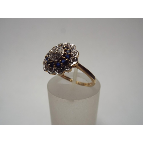 61 - 9ct Gold Diamond & Sapphire ring set in flower pattern.  2.8g Fomger size 'R'  IIV of £350