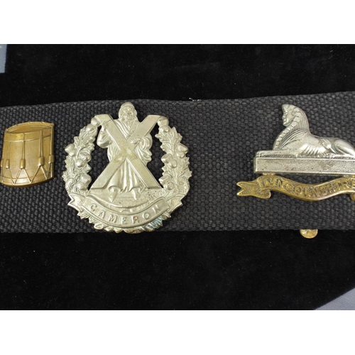 12 - A Navy Webbing Belt with 14 Regimental Cap badges attached.. WW1 MGC badge not original