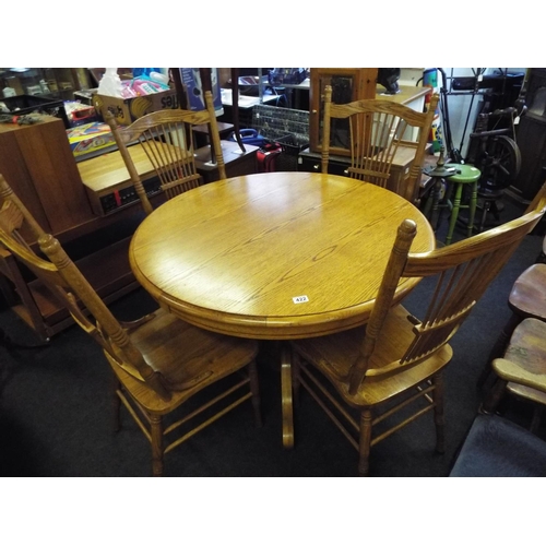 422 - A circular table with four stick back chairs in a light oak effect. Turned centre column .