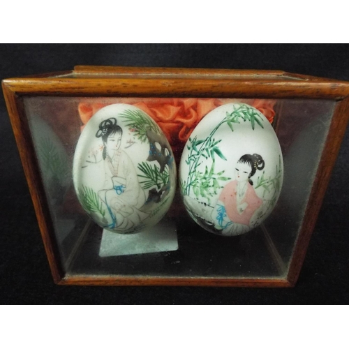 138 - Two oriental painted hens eggs in wood and glass case.