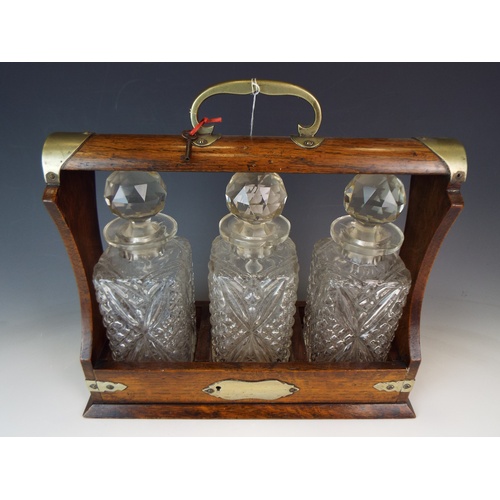 586 - Early 20th Century Oak and brass tantalus, Original matching pressed glass decanters. Key present.