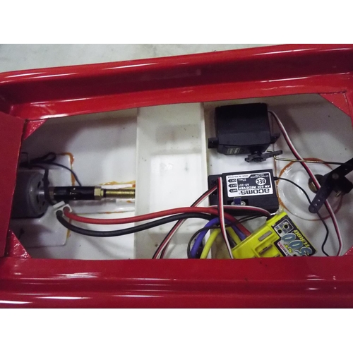 21 - Radio controlled plastic powerboat in wooden cradle. 20 inches long. Working condition unknown.