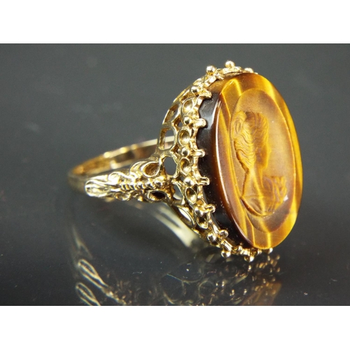 44 - 9ct Yellow gold Ring set with a carved Tiger's eye Cameo. Scrolled and Pierced shoulders.  Finger si... 