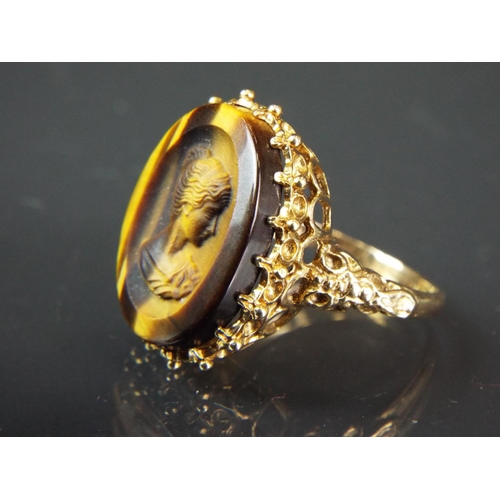 44 - 9ct Yellow gold Ring set with a carved Tiger's eye Cameo. Scrolled and Pierced shoulders.  Finger si... 