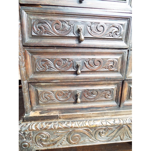 910 - Jacobean style dark Oak chest of drawers raised on a carved support with shelf under. Two wrought Ir... 