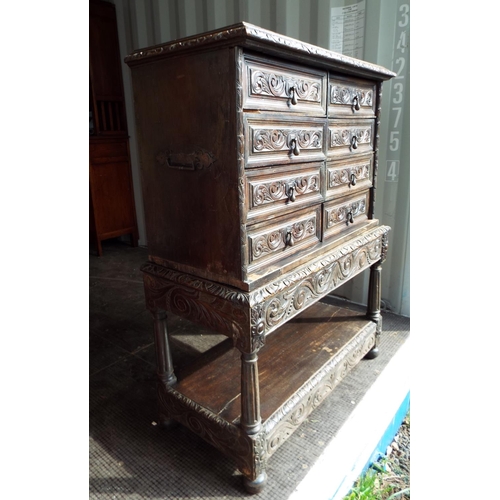 910 - Jacobean style dark Oak chest of drawers raised on a carved support with shelf under. Two wrought Ir... 