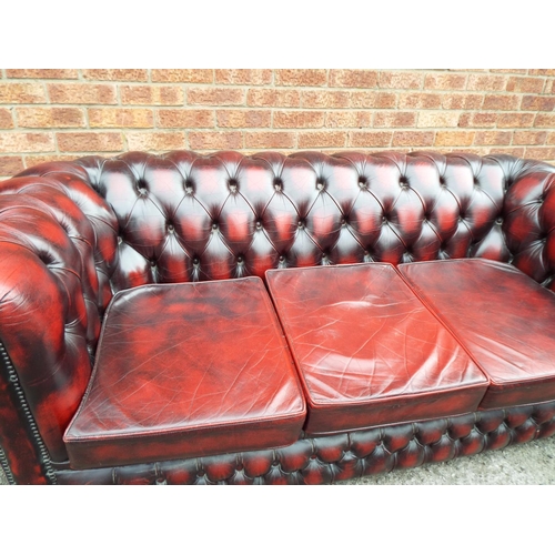 940 - Leather three seater Chesterfield in Oxblood, Raised on castors for easy movement. W:74 inches. See ... 