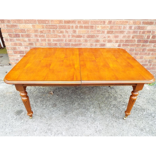 946 - Blonde wood dining table which stands on detachable fluted turned legs with brass castors .  H:31 x ... 