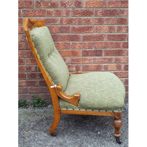 953 - light oak Nursing chair with carved decoration  Upholstered in a green material. Each on castors. Se... 