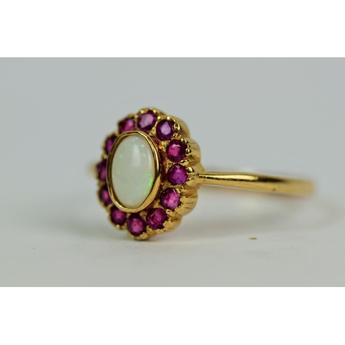 504a - 9ct Yellow gold ring set with a central Opal (7 x 5mm) Surrounded by a halo of 12 smaller Rubies.  F... 