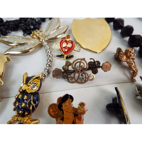 854 - Costume jewellery brooches, black beads, pin badges etc.