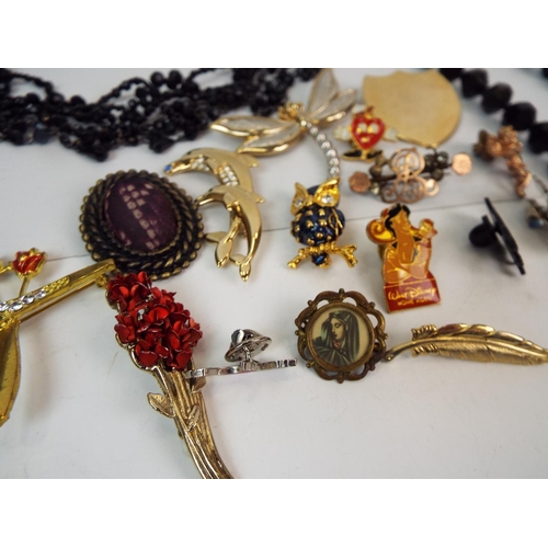 854 - Costume jewellery brooches, black beads, pin badges etc.