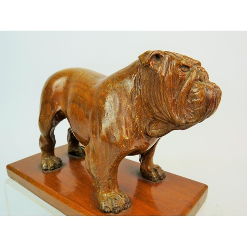 204 - Hand Carved wooden sculpture of a Bulldog raised on wooden plinth. Measures 7 inches long. 5 inches ... 