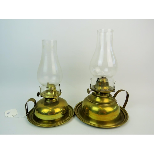 310 - Two Brass based hand held oil lamps with glass chimneys, the largest being 12 inches tall. See photo... 