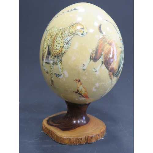 375 - Beautifully decorated Ostrich Egg supported by a hand carved piece of African Hardwood. Egg is decor... 