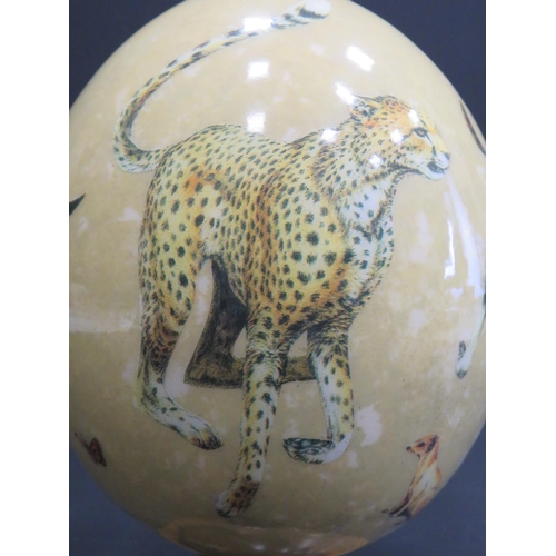 375 - Beautifully decorated Ostrich Egg supported by a hand carved piece of African Hardwood. Egg is decor... 