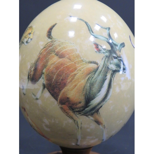 375 - Beautifully decorated Ostrich Egg supported by a hand carved piece of African Hardwood. Egg is decor... 