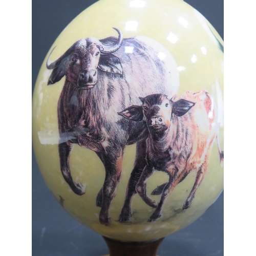 375 - Beautifully decorated Ostrich Egg supported by a hand carved piece of African Hardwood. Egg is decor... 