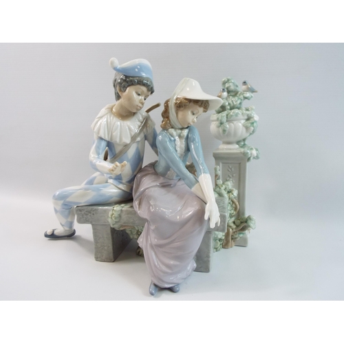 281 - Large Nao Lladro figurine of a Harlequin boy and girl seated in a walled garden, 9