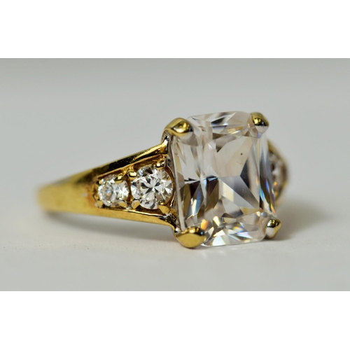 222 - 9ct Yellow Gold ring set with a large Emerald Cut CZ Gemstone accompanied by smaller Brilliant cut s... 