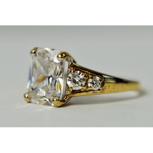 222 - 9ct Yellow Gold ring set with a large Emerald Cut CZ Gemstone accompanied by smaller Brilliant cut s... 