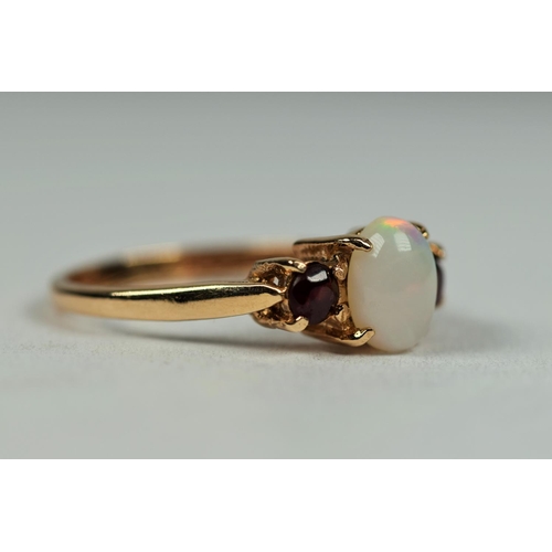 493 - 9ct Yellow Gold ring set with a central oval white opal with two Garnets in attendance.  Finger size... 