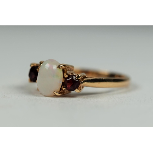 493 - 9ct Yellow Gold ring set with a central oval white opal with two Garnets in attendance.  Finger size... 